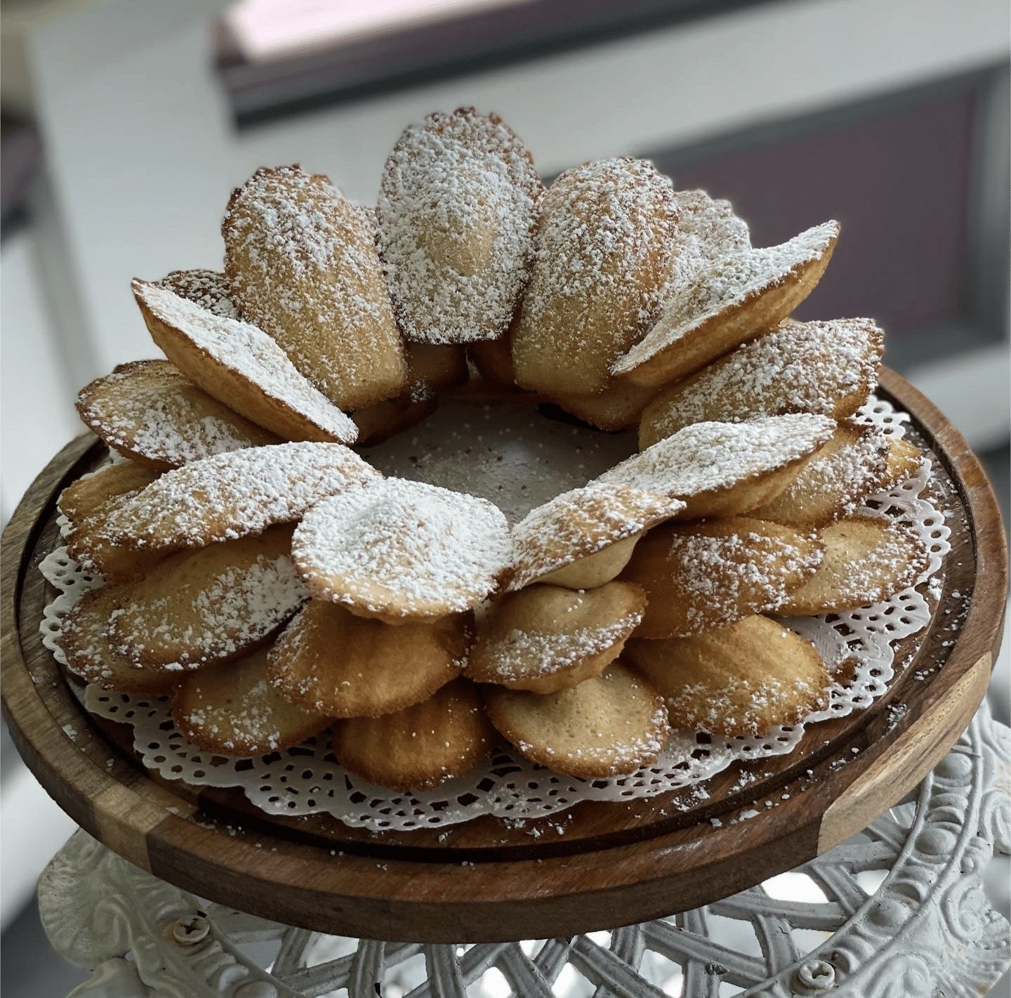 a plate of madeline cookies covered in powdered sugar