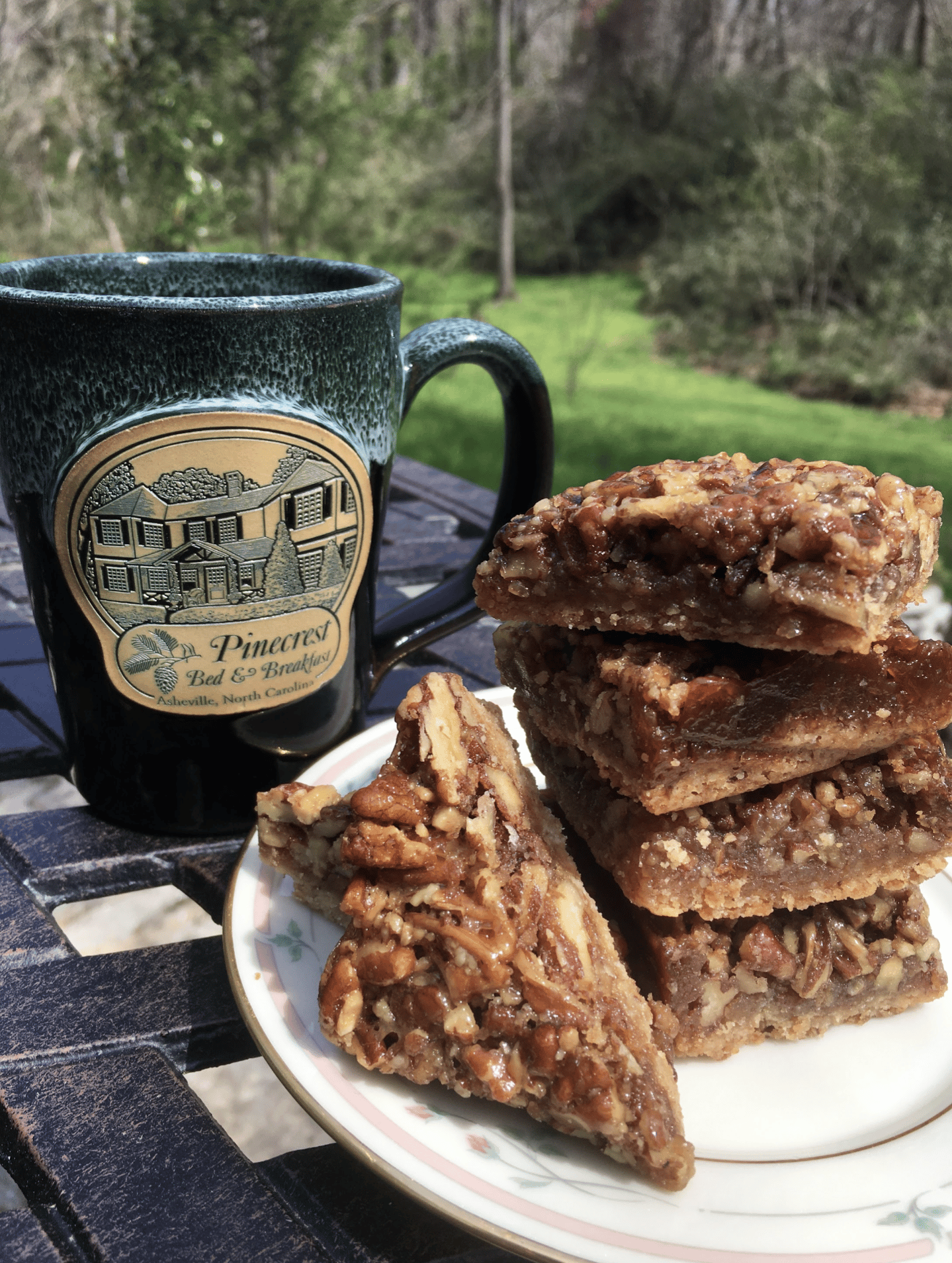 a stack of pecan bar cookies on a plate beside a green mug