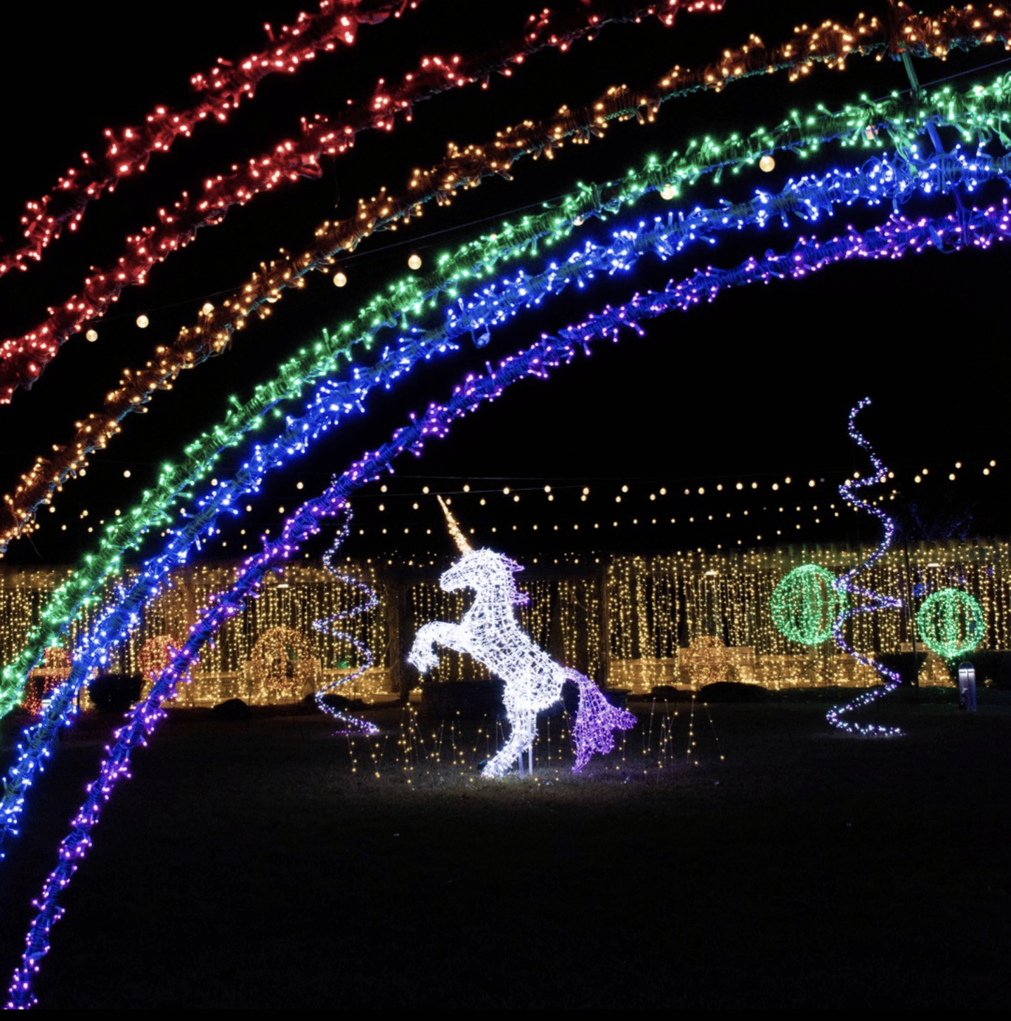 Night with christmas lights forming a rainbow over a unicorn