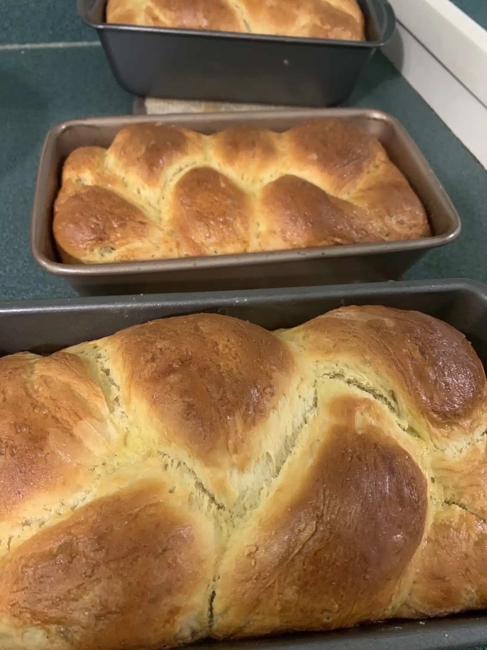three loaves of challah bread in pans