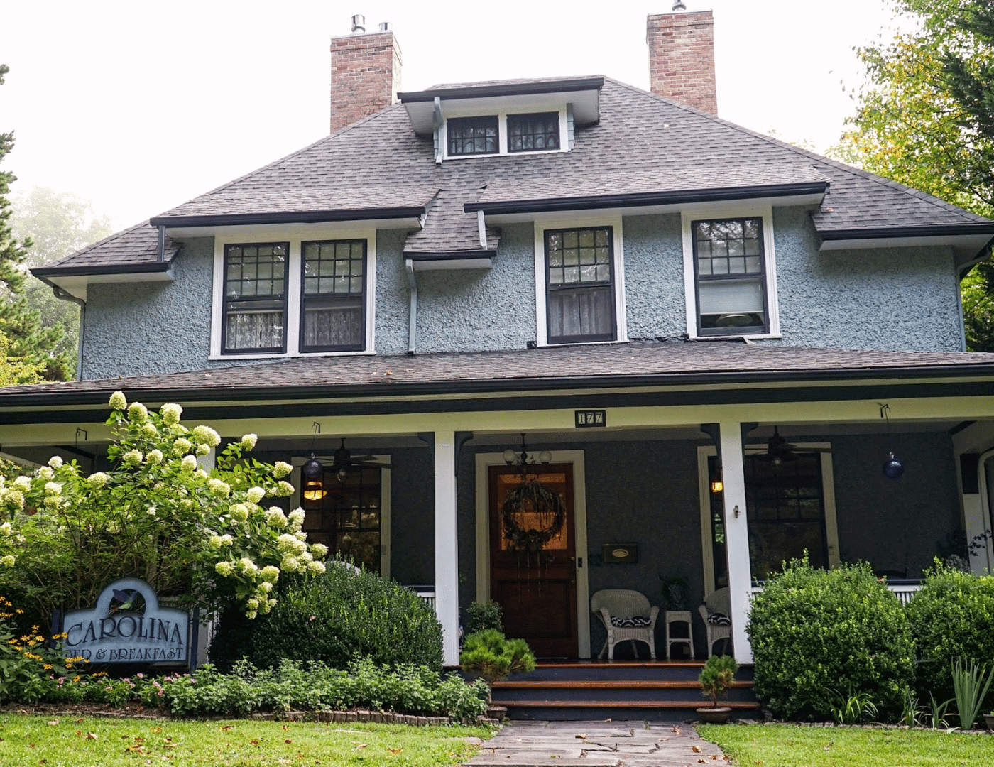 a blue stucco 3 story B&B with a deep front porch and white trim