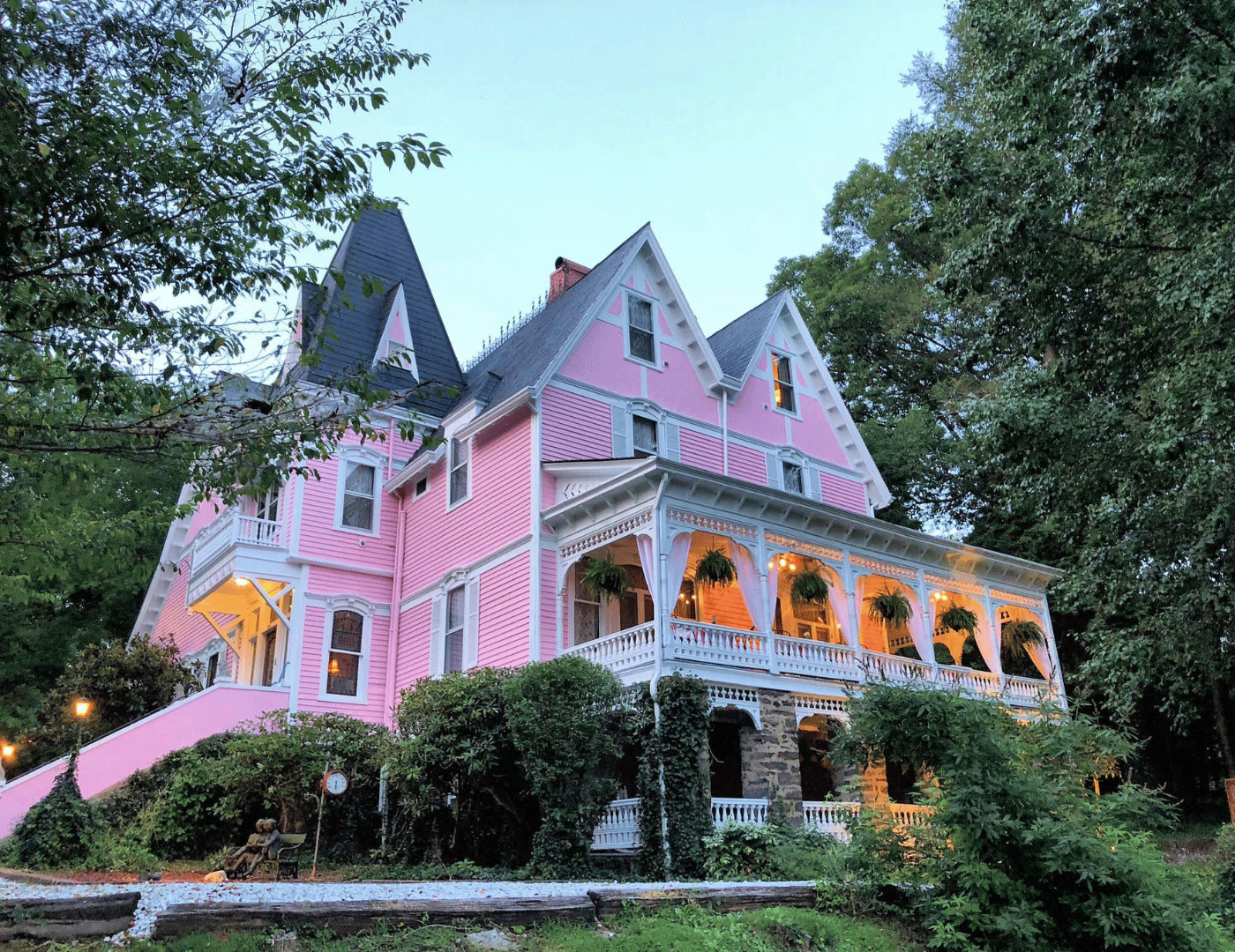 a pink Victorian 4-story B&B with white gingerbread trim on the side porch