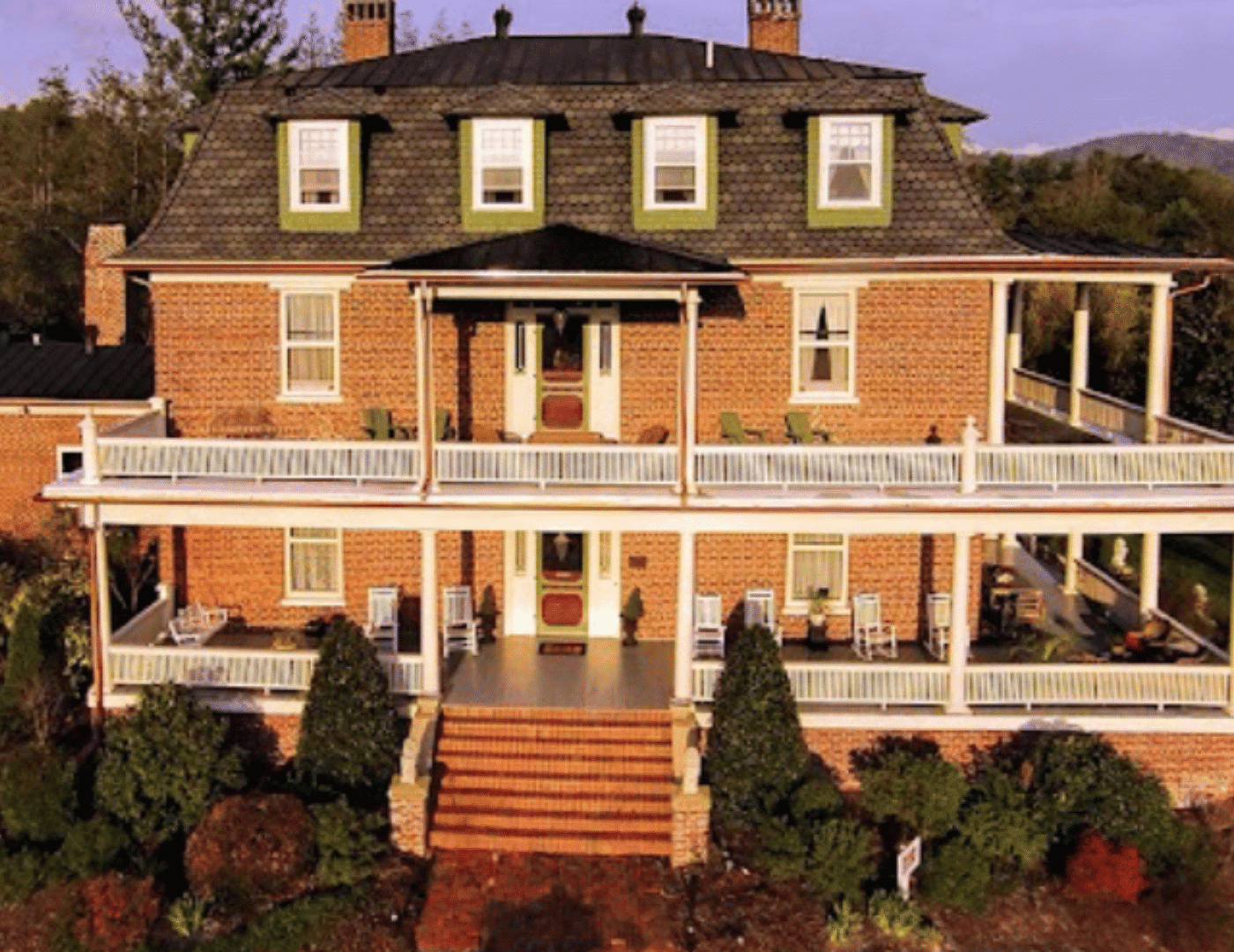drone photo of 3-story brick B&B with wrap around porches and mansard roof