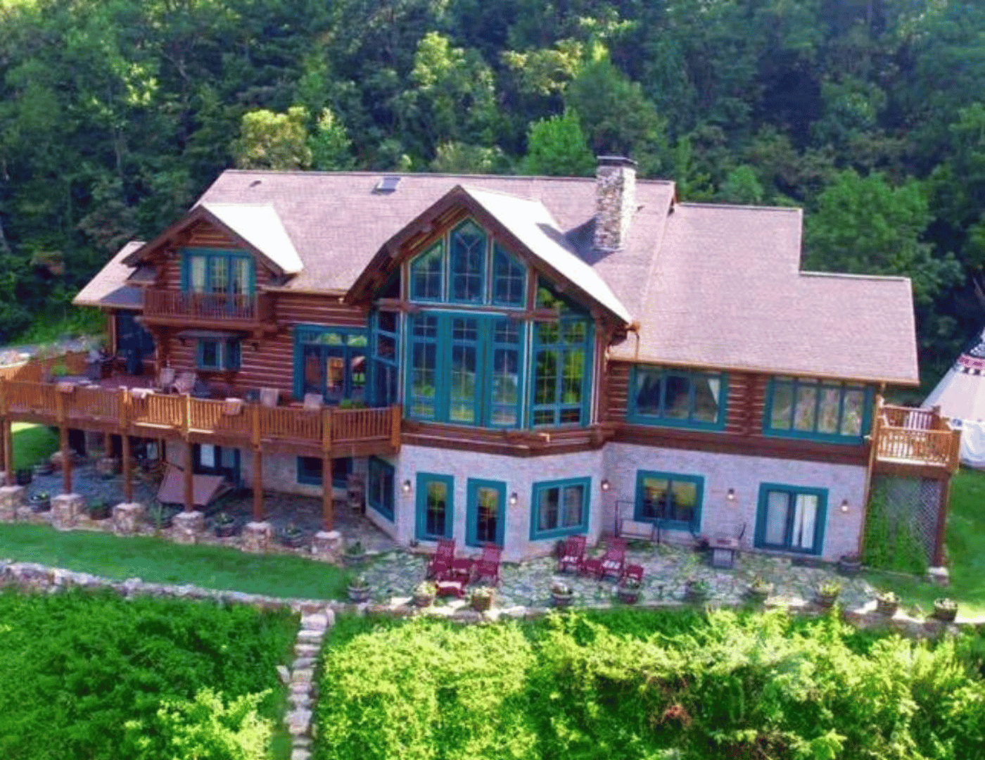 drone photo of 3 story log cabin lodge with large a-frame windows and decks