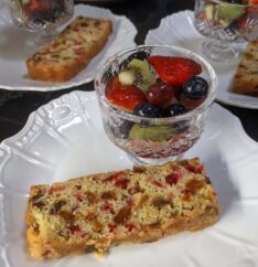 A breakfast plate with fruit in a crystal cup and a slice of cranberry walnut bread