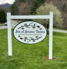 A white sign in a green field that says Inn at Amaris Farms